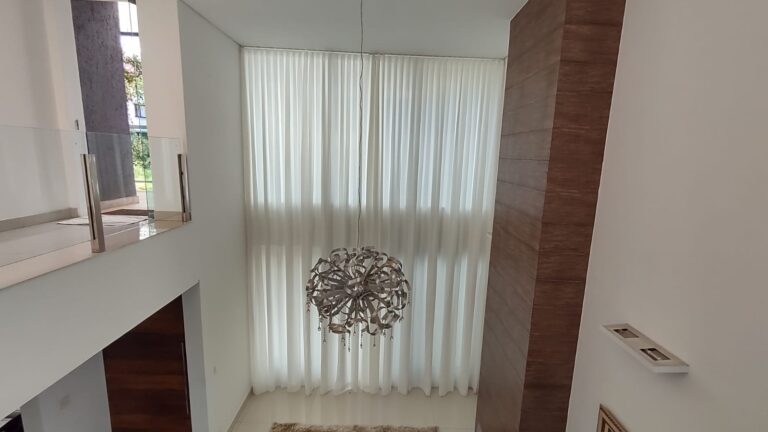 Cortina translúcida em sala com pé-direito duplo: a automação permite controlar a entrada de luz com um comando.
